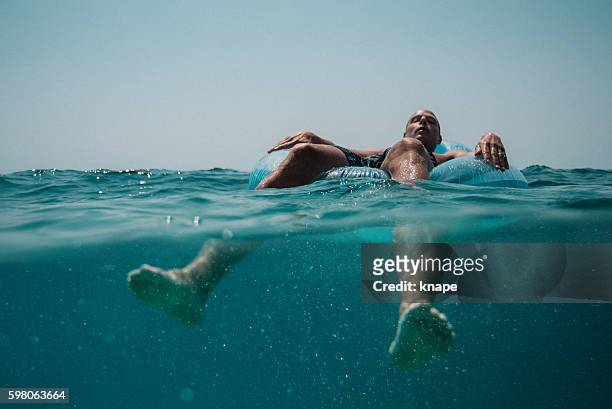 man floating in the mediterranean sea in croatia - pool raft imagens e fotografias de stock