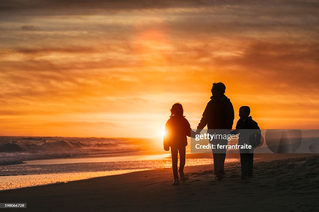 Family walk by the beach at sunset