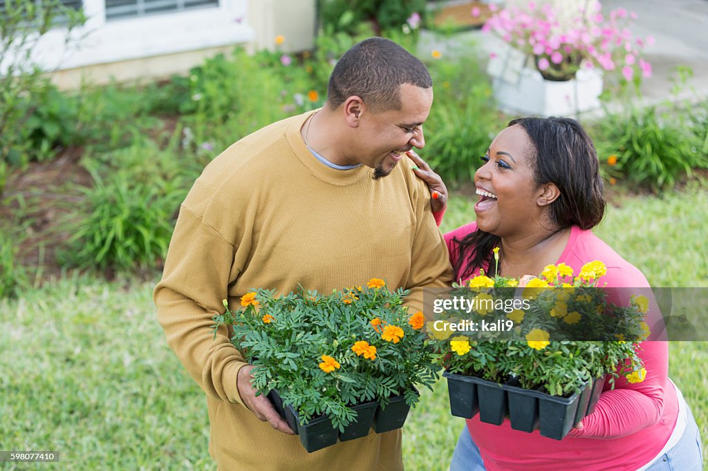 Young black couple outside home planting flowers
