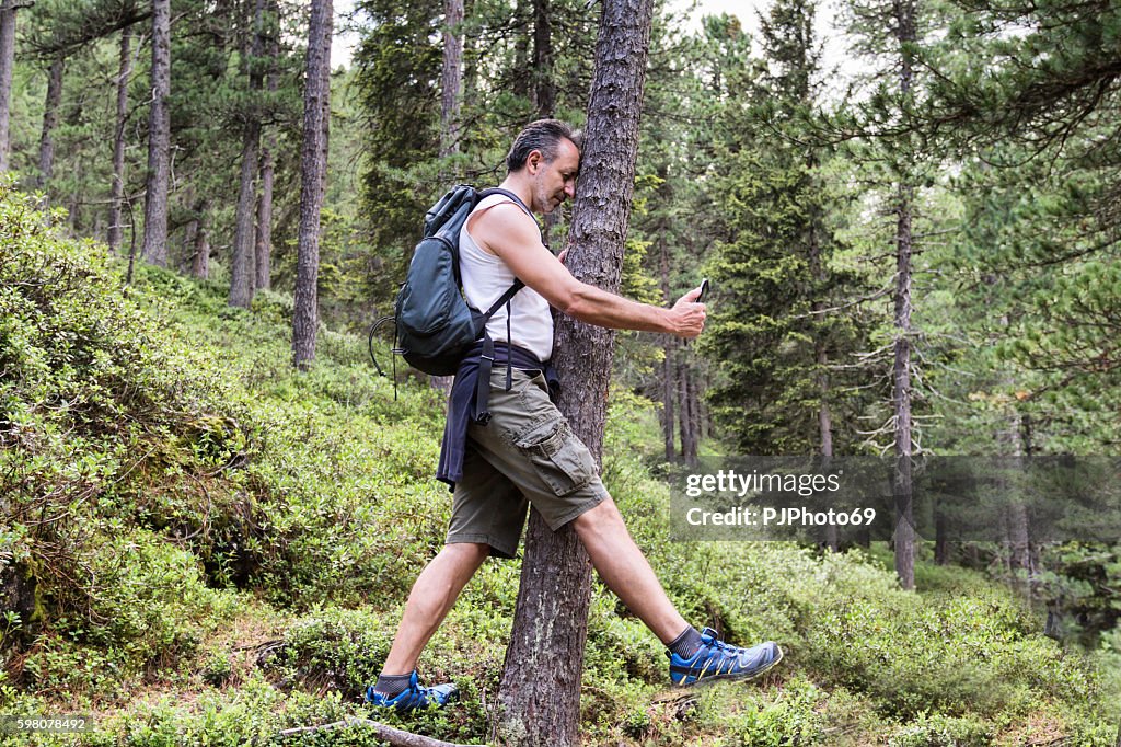 Mann schlägt gegen Baum spielen PokemonGo auf seinem Smartphone