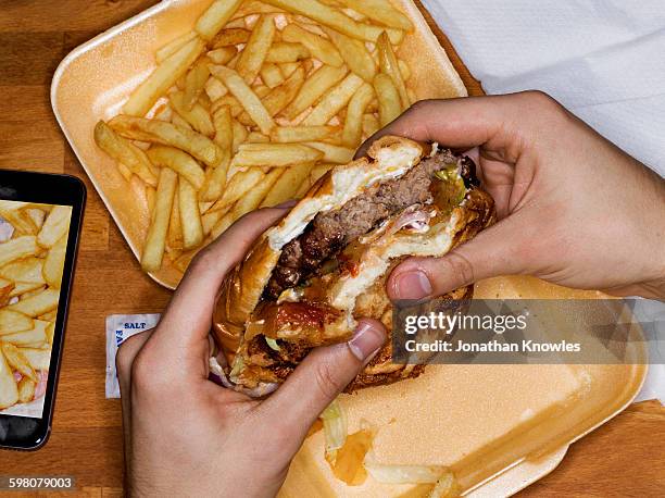 men eating hamburger and fries, phone with picture - take out food foto e immagini stock