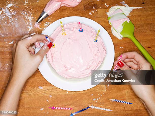 female putting candles on a pink cake - moments daily life from above photos et images de collection