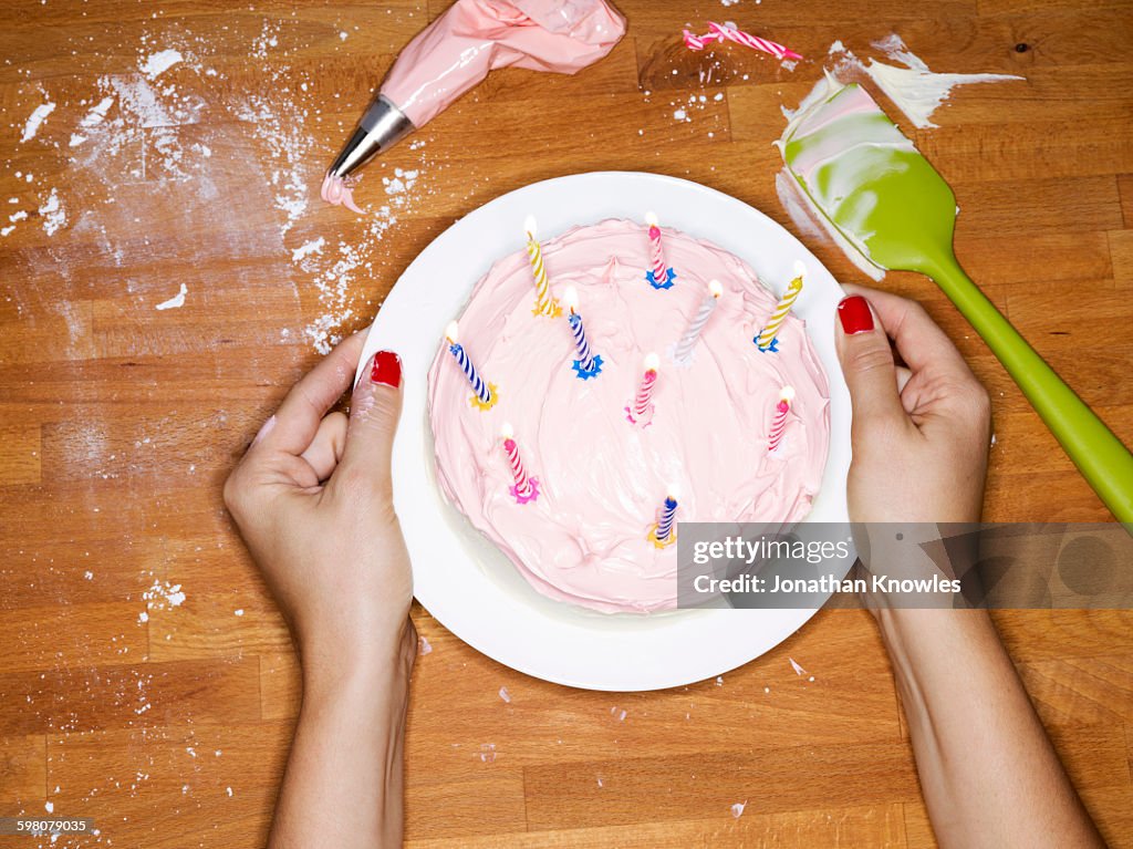 Female presenting cake with lit candles