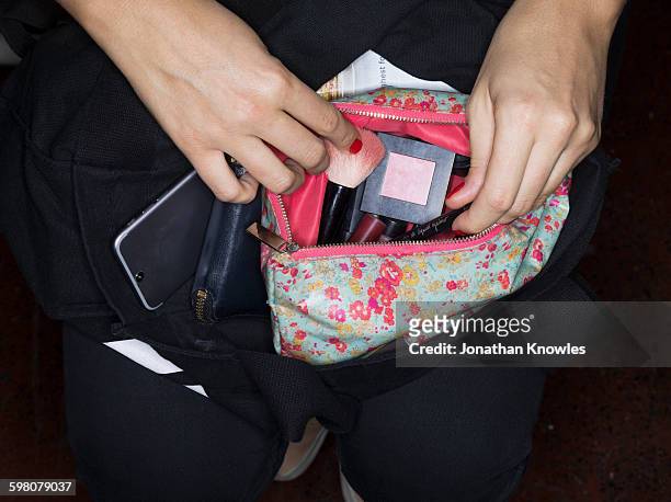 female going through her make up bag, close up - multi coloured purse stockfoto's en -beelden