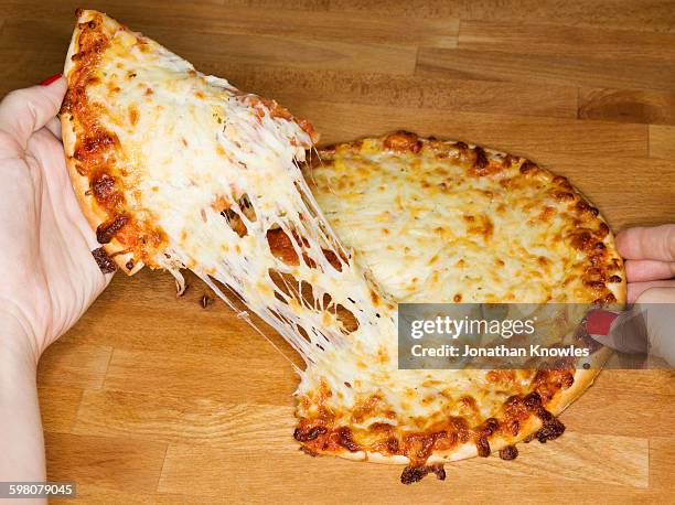 female taking a slice from pizza, elevated view - pulling stock pictures, royalty-free photos & images