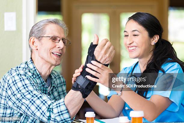 friendly nurse examines senior patient's wrist - orthopaedic equipment stock pictures, royalty-free photos & images
