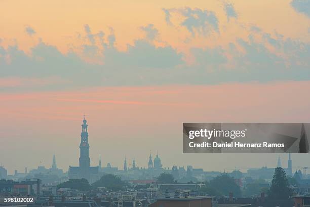 distant view of amsterdam skyline with the church westerkerk in background at sunrise - amsterdam skyline stockfoto's en -beelden