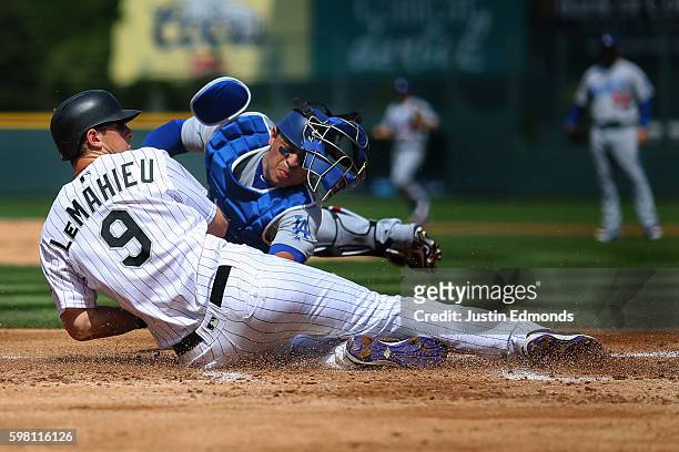 LeMahieu of the Colorado Rockies slides to score ahead of the tag from catcher Carlos Ruiz of the Los Angeles Dodgers on a double off the bat of...