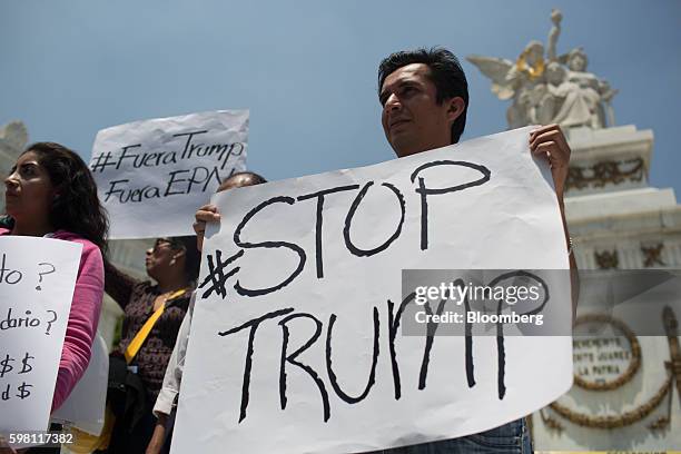 Demonstrators hold signs protesting the visit of Donald Trump, 2016 Republican presidential nominee, to Mexico for a meeting with Enrique Pena Nieto,...