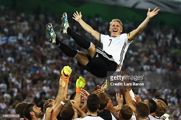 Bastian Schweinsteiger of Germany is thrown in to the air by team mates after his last international match during the International Friendly match...
