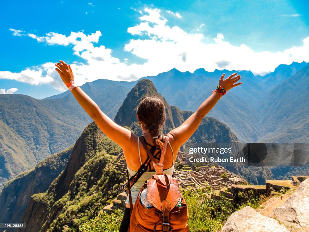 Woman rising hands looking at Machu Picchu