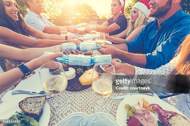 group of people pulling christmas crackers. - sky crackers stock pictures, royalty-free photos & images