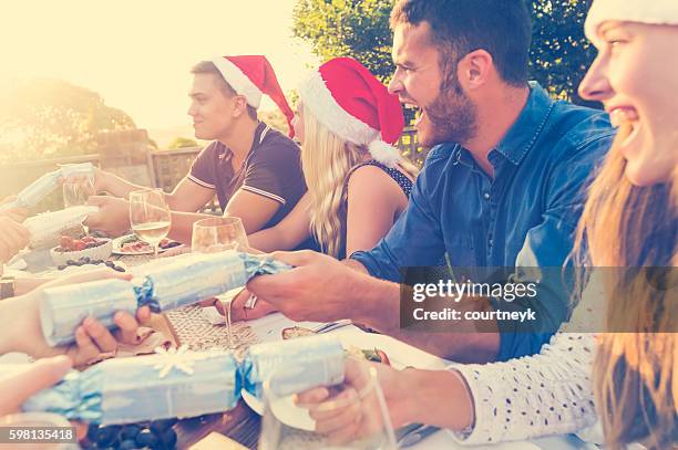group of people pulling christmas crackers. - christmas crackers stock pictures, royalty-free photos & images