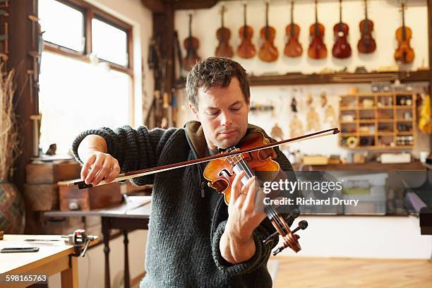 craftsman testing instrument in repair workshop - string instrument stock pictures, royalty-free photos & images