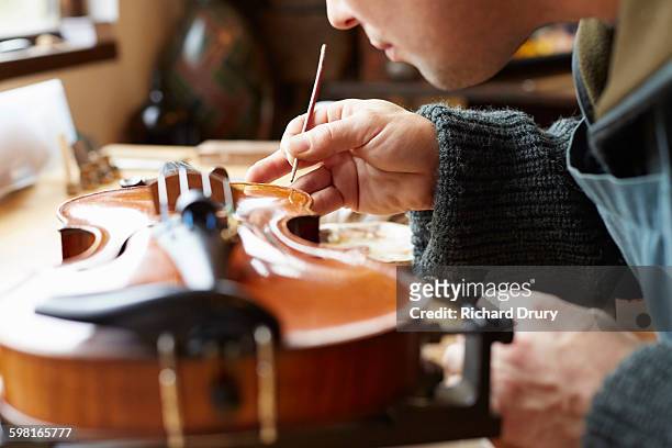 retouching varnish in violin repair workshop - instrumentenmaker stockfoto's en -beelden