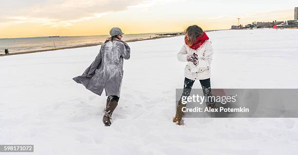 two sisters, teenager girls, play snowballs at the brighton beach - enterntainment stock pictures, royalty-free photos & images