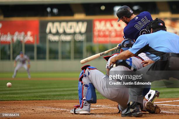 David Dahl of the Colorado Rockies hits an RBI single during the first inning as catcher Yasmani Grandal of the Los Angeles Dodgers and umpire Phil...