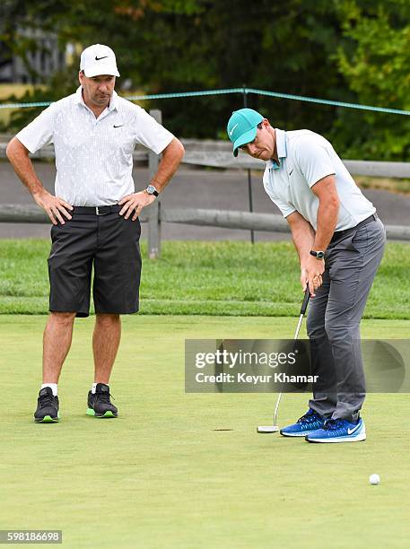 Rory McIlroy of Northern Ireland putts on the practice green with his caddie J.P. Fitzgerald prior to the Deutsche Bank Championship at TPC Boston on...