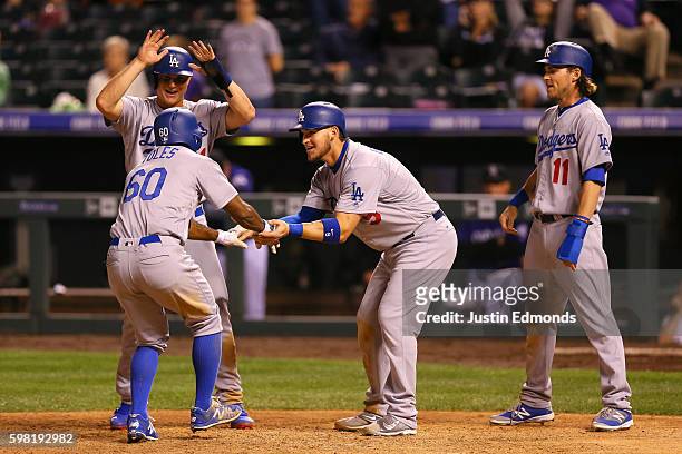 Andrew Toles of the Los Angeles Dodgers is greeted at home plate by Joc Pederson, Yasmani Grandal and Josh Reddick after hitting a go-ahead grand...