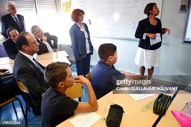 French President Francois Hollande looks on with director of the school in a classroom during a visit at the high school Jean Rostand for the first...