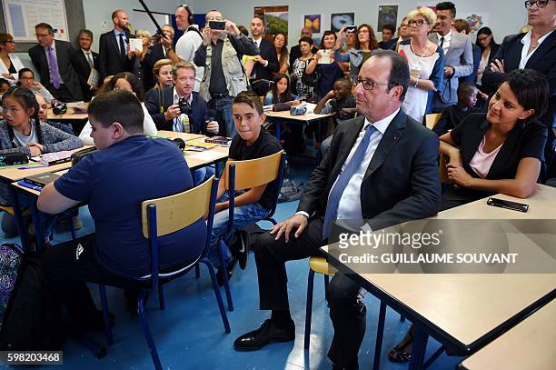 French President Francois Hollande sits with French Minister of Education Najat Vallaud-Belkacem in a classroom as they look on during a visit at the...