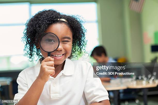 pretty african american girl looks through magnifying glass - child magnifying glass stock pictures, royalty-free photos & images