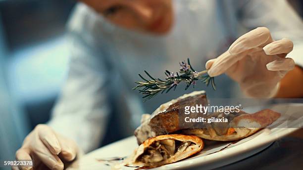 chef che mette gli ultimi ritocchi su un pasto. - gourmet foto e immagini stock