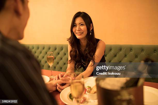 幸せに彼女のボーイフレンドの手を握っている女性 - intimate dinner ストックフォトと画像