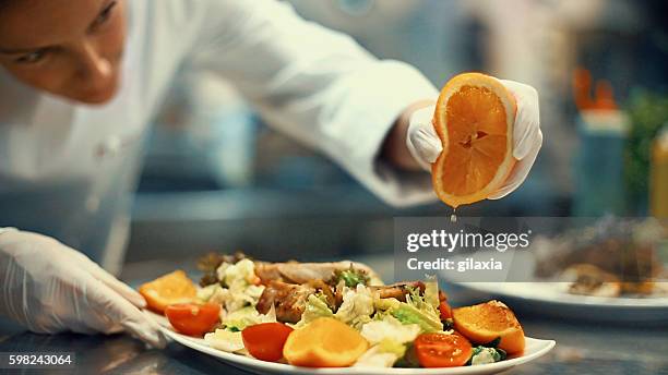 chef placing finishing touches on a meal. - woman squeezing orange stockfoto's en -beelden