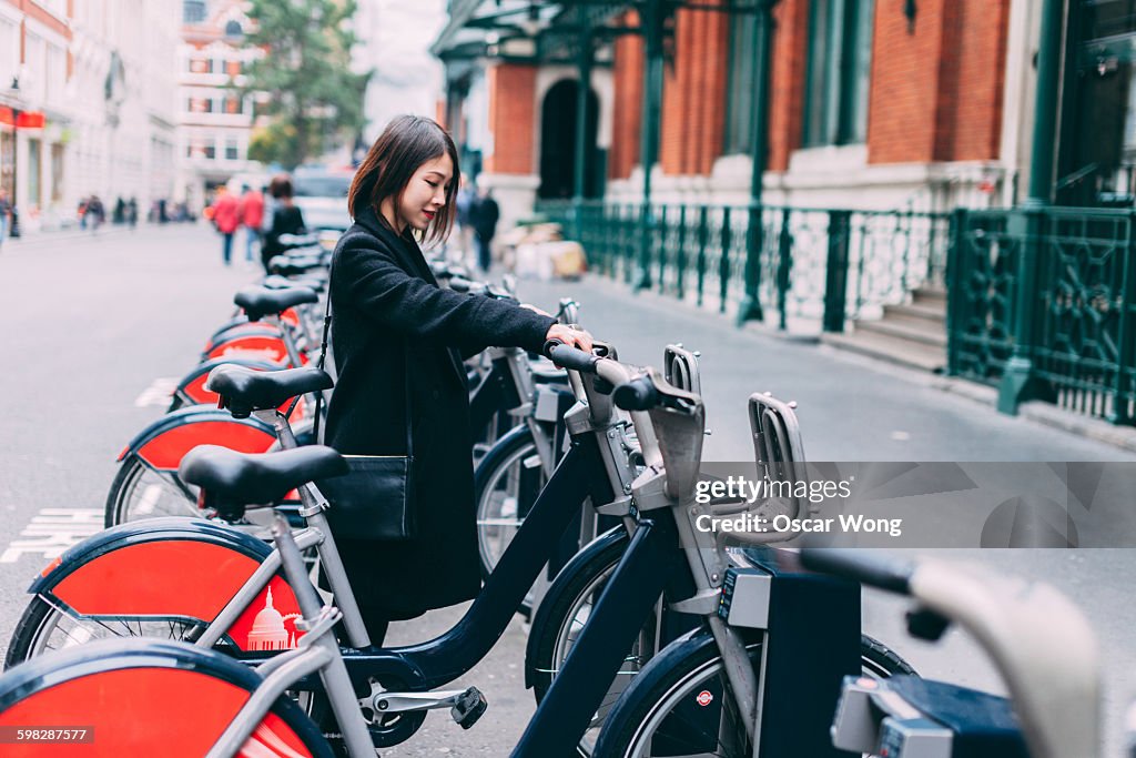 Young woman renting bicycle on street in London