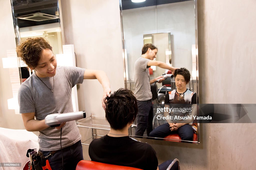 Young hairdresser blowing hair