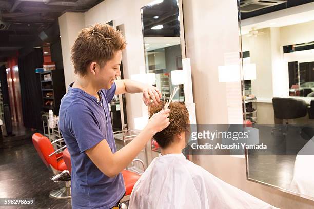 young hairdresser cutting hair - atsushi yamada stock pictures, royalty-free photos & images