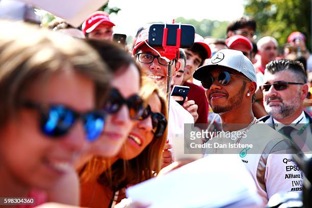 Lewis Hamilton of Great Britain and Mercedes GP gets his photo taken with a fan as he arrives at the circuit during previews for the Formula One...