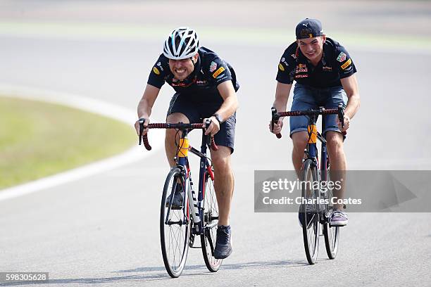 Max Verstappen of Netherlands and Red Bull Racing rides a bicycle with race engineer Gianpiero Lambiase on the track during previews for the Formula...