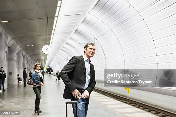 businessman putting mobile phone in pocket while standing at railroad station platform - 50 metros 個照片及圖片檔