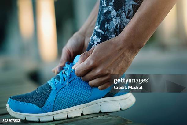 close-up of woman tying shoelace on bench - running shoes close up stock-fotos und bilder