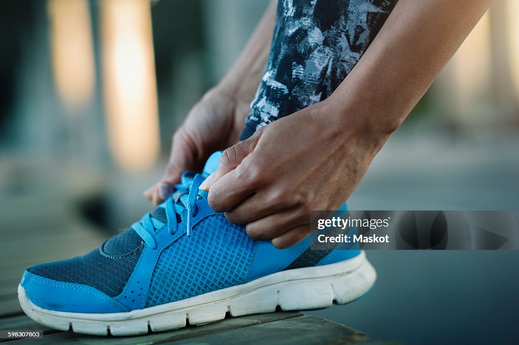 Close-up of woman tying shoelace on bench