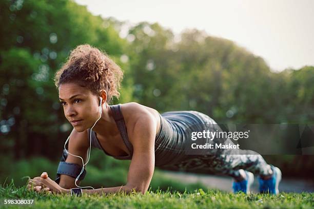 sporty woman doing plank exercise at park - postura de plancha fotografías e imágenes de stock