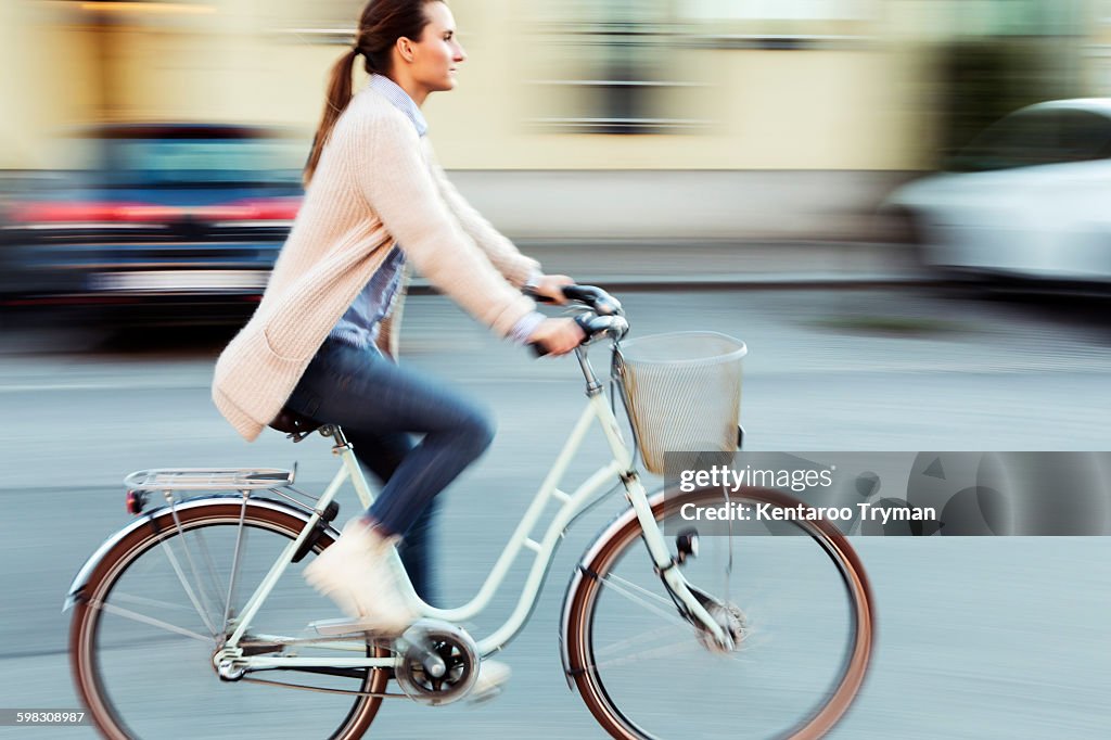 Side view of businesswoman riding bicycle on road