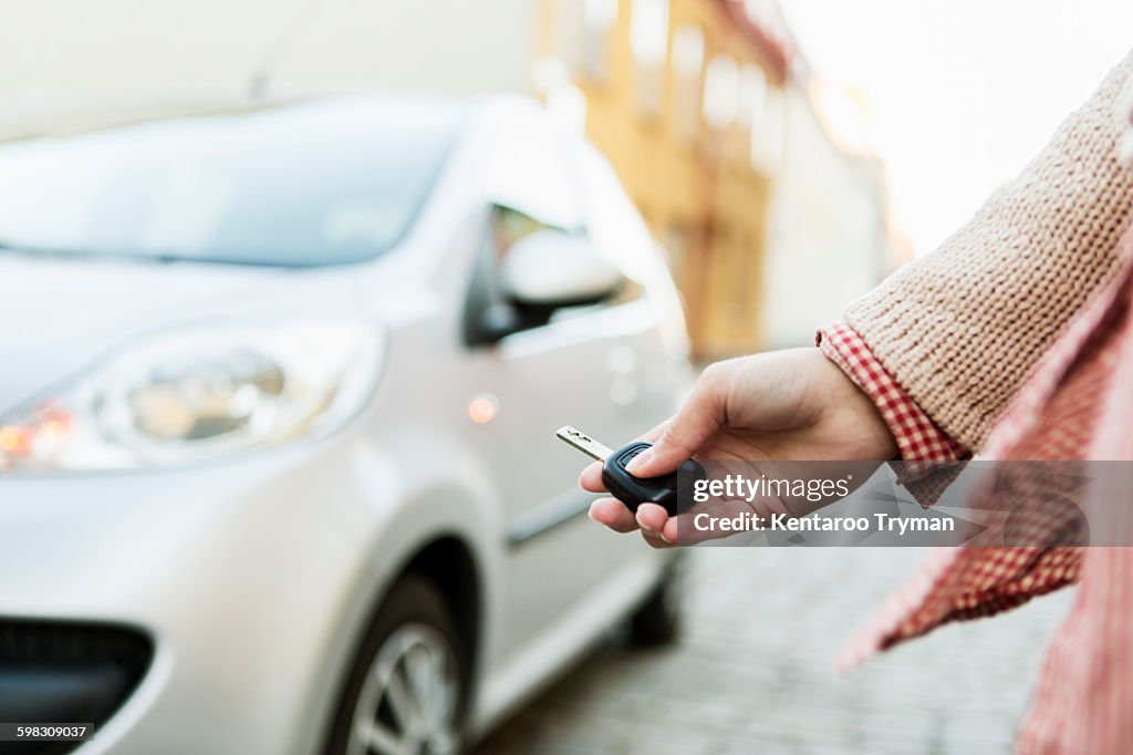 Cropped image of businesswoman using remote control key to unlock car