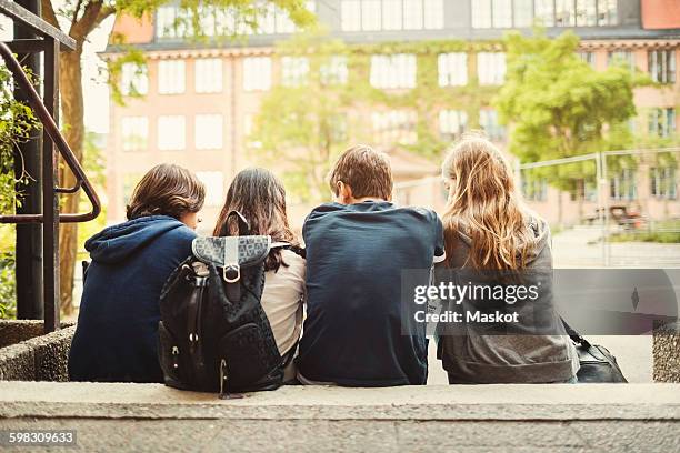 rear view of teenagers sitting on steps outdoors - school playground stock-fotos und bilder