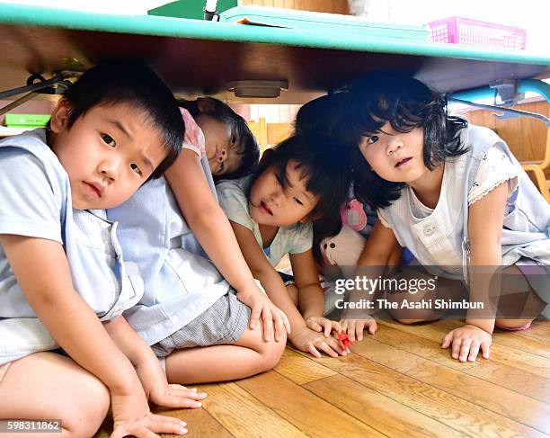 Kindergarten children evacuate under tables during an emergency drill on September 1, 2016 in Toyama, Japan. Emergency drills are held across the...