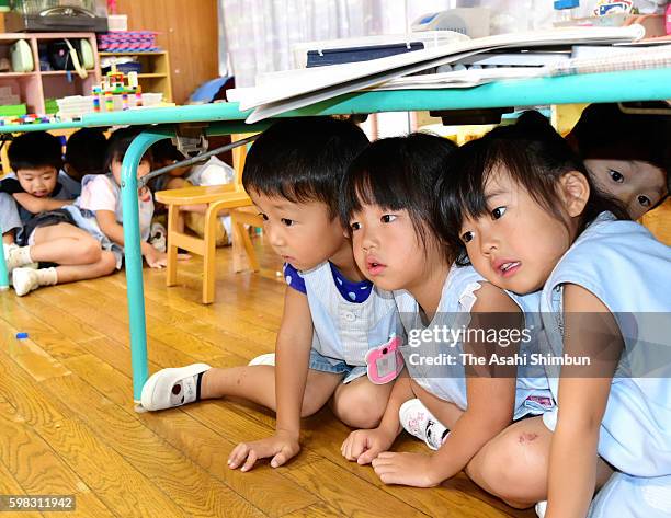 Kindergarten children evacuate under tables during an emergency drill on September 1, 2016 in Toyama, Japan. Emergency drills are held across the...
