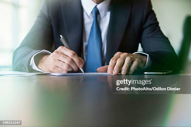 businessman doing paperwork - signer photos et images de collection