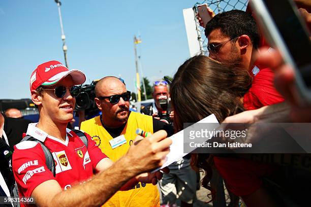 Sebastian Vettel of Germany and Ferrari signs autographs for fans as he arrives at the circuit during previews for the Formula One Grand Prix of...