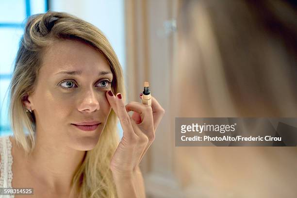 woman applying cosmetics - concealer stock pictures, royalty-free photos & images