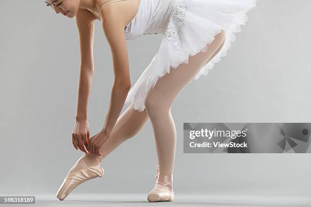 young woman is a ballet shoe lace - bending over in skirt stock-fotos und bilder