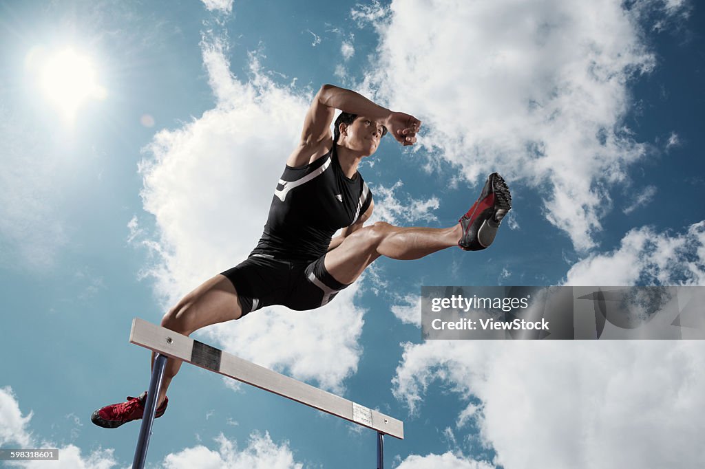 Track and field athletes in hurdle race