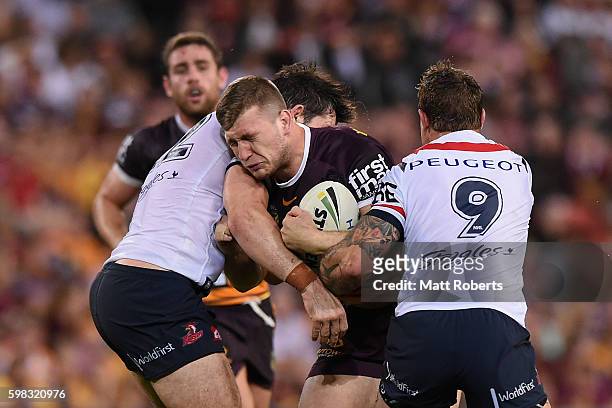 Jai Arrow of the Broncos is tackled by Aidan Guerra and Jake Friend of the Roosters during the round 26 NRL match between the Brisbane Broncos and...