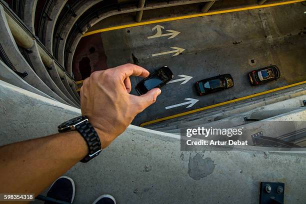 guy from personal point of view playing with perspective in a nice and creative view in a concrete parking garage holding little cars with his hands like toys. - perspektive stock-fotos und bilder